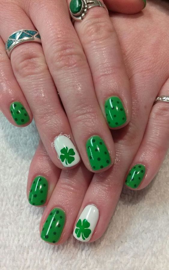 Human hand with nails painted with a rainbow with a clover design and clover nail art design