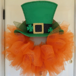 Leprechaun hat wreath with orange deco mesh hanging on a white front door