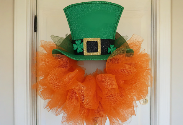 Leprechaun hat wreath with orange deco mesh hanging on a white front door