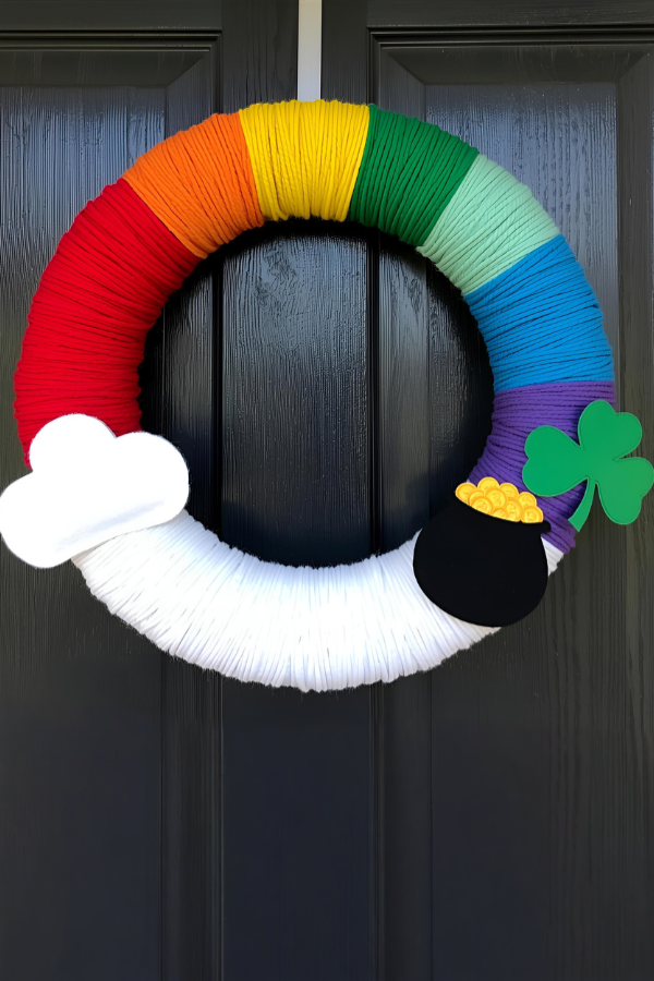 St. Patrick’s Day rainbow wreath with pot of gold and cloud hanging on a wooden door