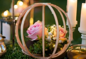 Fairytale bridal shower centerpiece with pink roses, greenery, and a delicate gold wire carriage surrounded by glowing candles