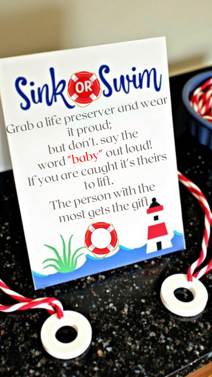 Nautical-themed baby shower game sign reading 'Sink or Swim,' instructing guests to wear a life preserver necklace and avoid saying the word 'baby.' If caught, others can take their life preserver, and the person with the most at the end wins a gift. The sign features ocean waves, a lighthouse, and life preserver graphics, with candy-striped necklaces on a black countertop.