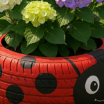 Creative ladybug-themed tire planter with blooming hydrangeas on a grassy lawn.