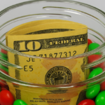 Creative money gift idea with cash hidden inside a jar of red and green candies.