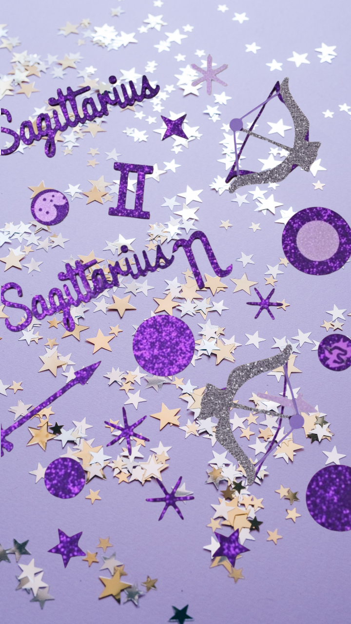Sagittarius confetti decor with purple glitter, stars, and zodiac symbols on pastel backdrop.