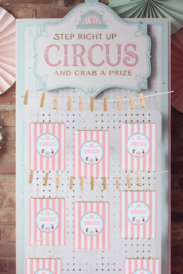 Dream Circus pastel grab a prize setup with a soft pegboard, pastel striped treat boxes, whimsical carnival sign, and paper rosettes against a brick wall.