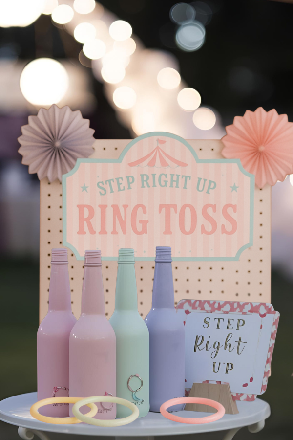 A carnival-style ring toss game with colorful bottles and rings.