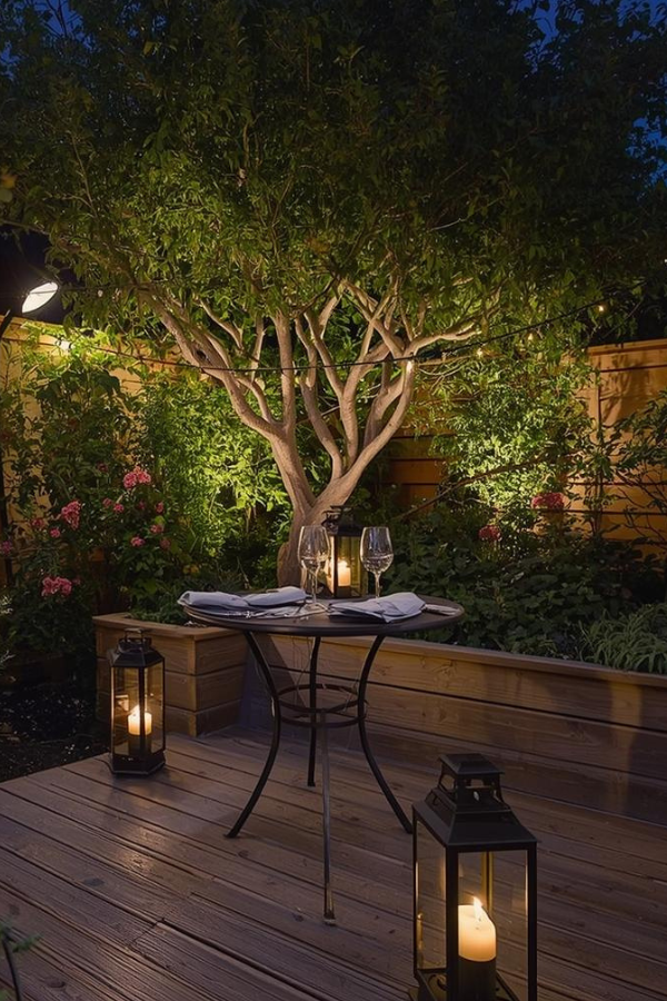 Soft winter garden lighting with lanterns and fairy lights highlighting an outdoor seating area at dusk