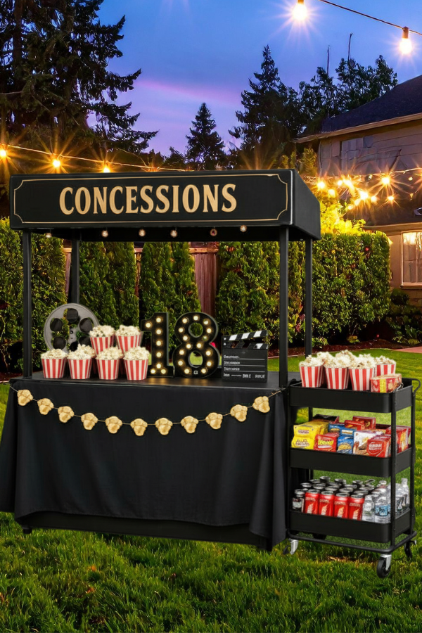 Backyard movie-themed concessions stand with popcorn, snacks, and drinks.